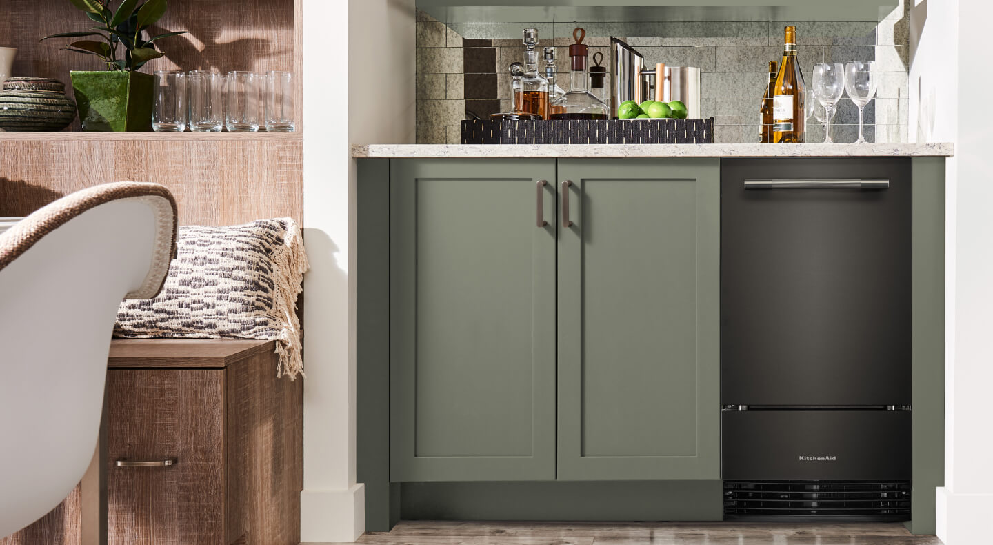Black Ore KitchenAid® ice maker in sage green cabinetry of a drink nook