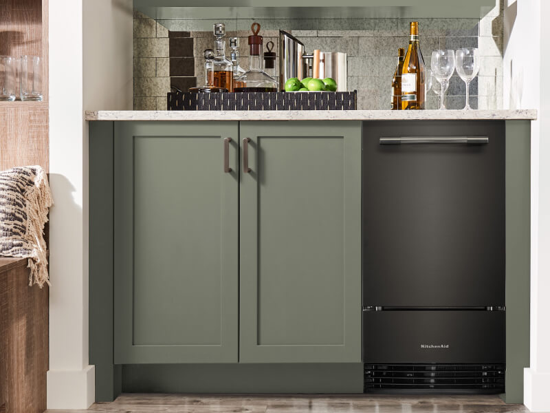 Black Ore KitchenAid® ice maker in sage green cabinetry of a drink nook