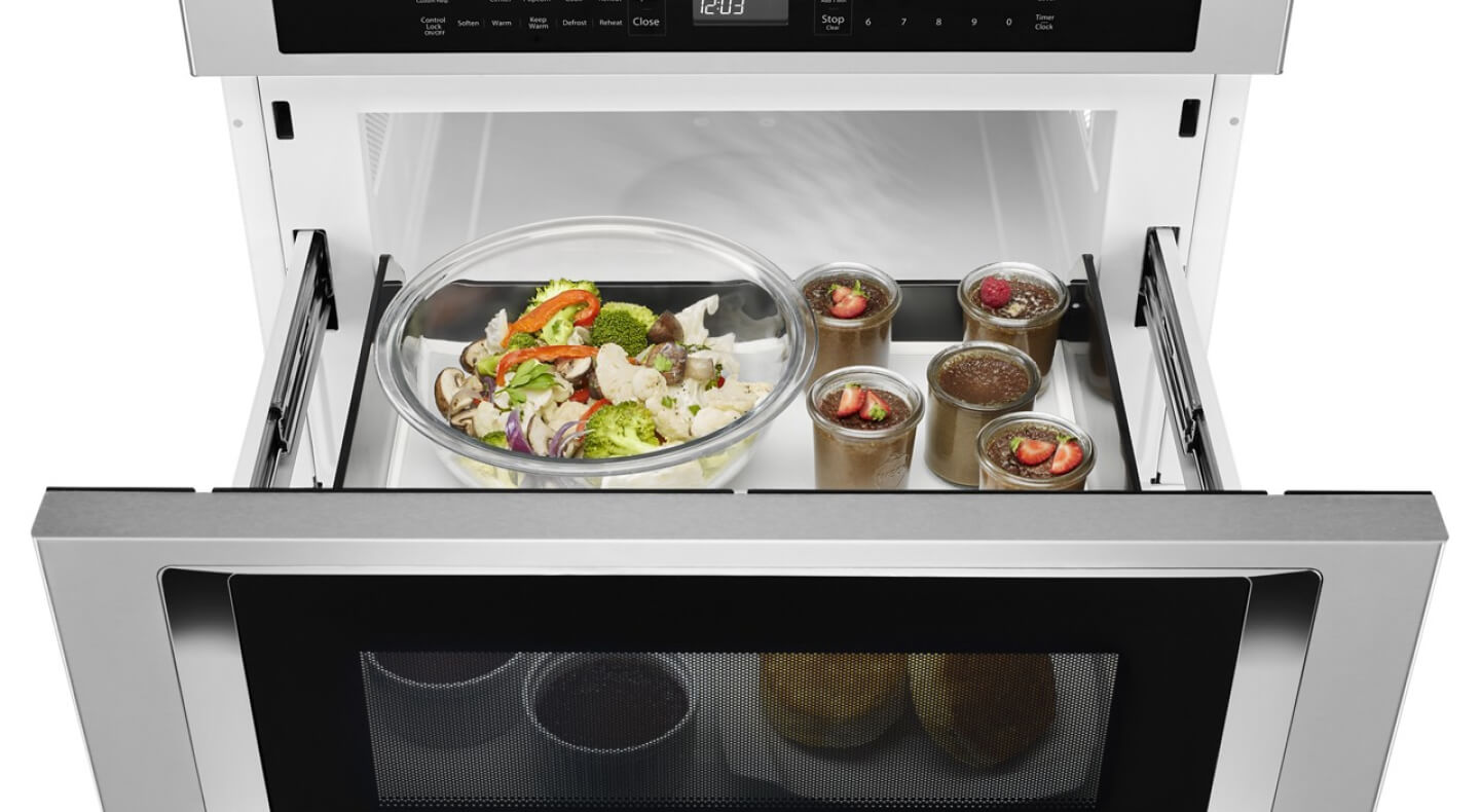An open KitchenAid® undercounter microwave oven drawer with an assortment of food inside