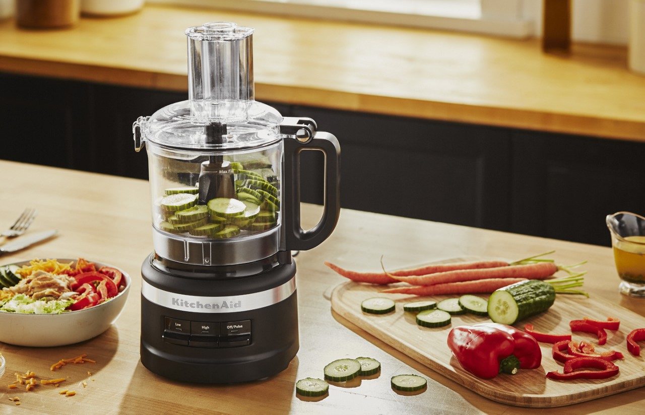 A food chopper with sliced cucumbers inside.