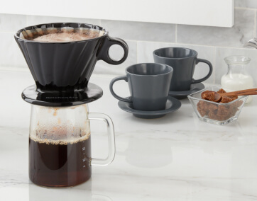 KitchenAid® Pour Over Coffee Maker with 2 gray coffee cups and cream and sugar on countertop.