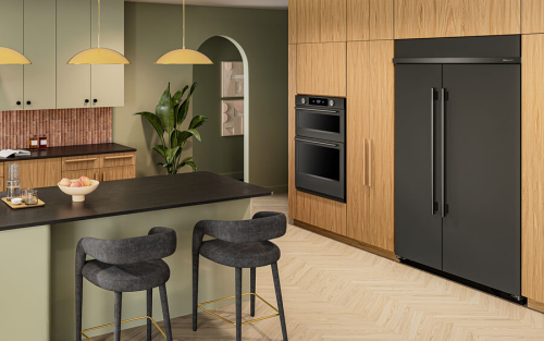 Built-in KitchenAid® refrigerator and wall oven in light wood cabinetry of open kitchen