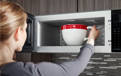 A person placing a bowl in a KitchenAid® microwave
