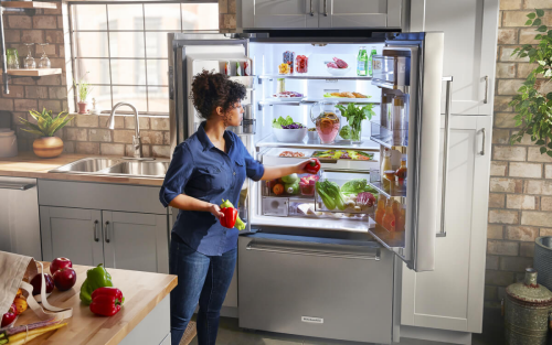 Person loading product into the crisper drawer of a French door refrigerator