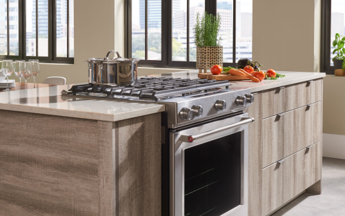 Kitchen island with electric cooktop in a modern kitchen with light wood cabinetry