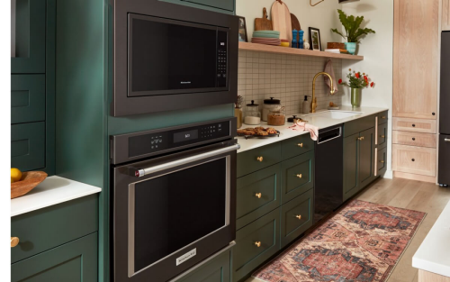 Suite of black stainless steel KitchenAid® appliances in green and natural brown cabinetry