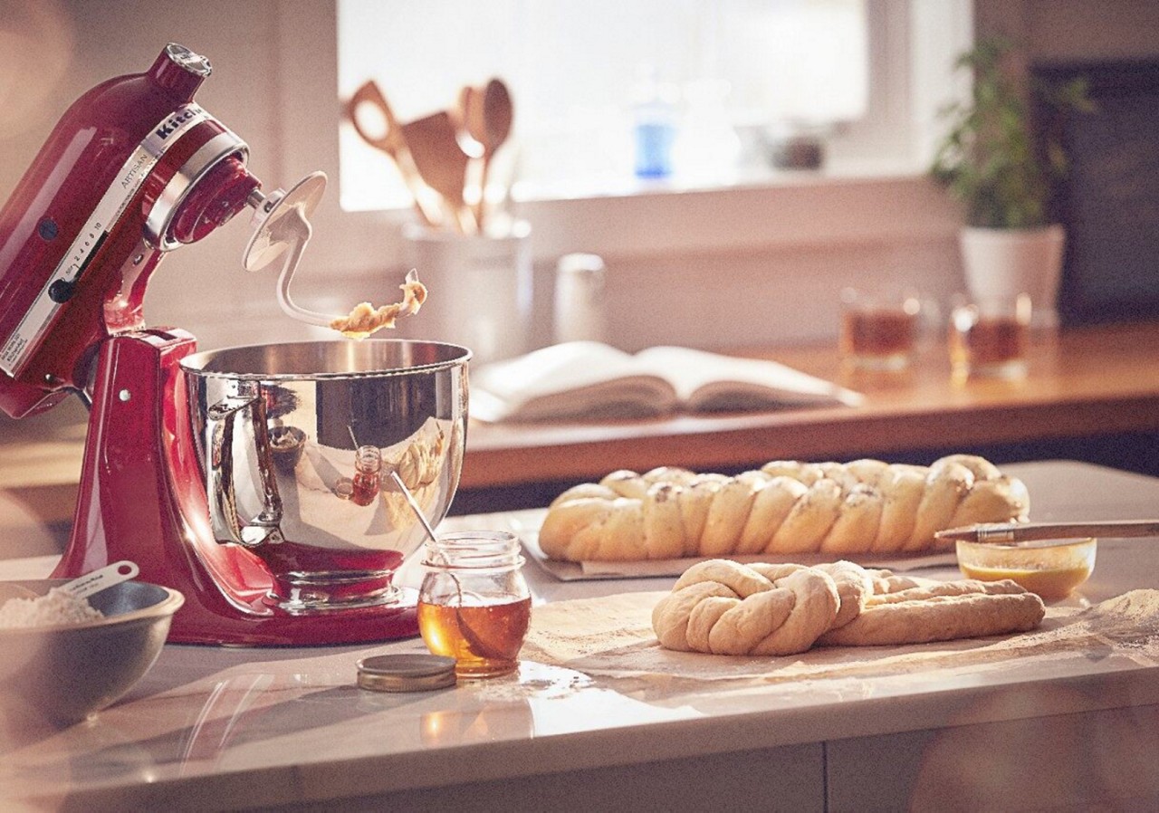 Red KitchenAid® stand mixer with dough hook attachment next to bread dough on counter