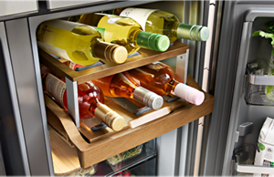 Wine bottles on a wooden sliding shelf inside of a KitchenAid® refrigerator
