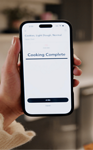 A person holding a phone with a Cooking Complete notification