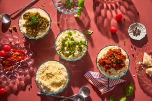 A several bowls of dips on a tabletop.