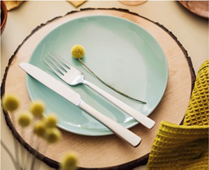 A tablesetting for one with a charcoal gray napkin, a glazed teal plate and decorative yellow flowers