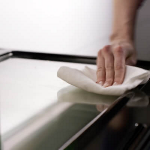 Person wiping oven door glass with a cloth