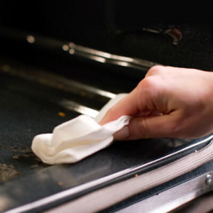 Person wiping down the interior of an oven