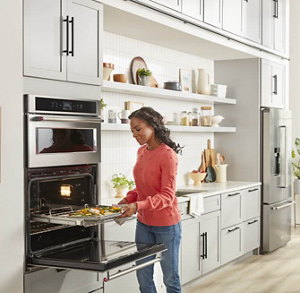 Person placing a baking sheet of vegetables in an oven