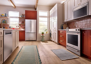 A suite of KitchenAid® stainless steel appliances in a burnt orange kitchen
